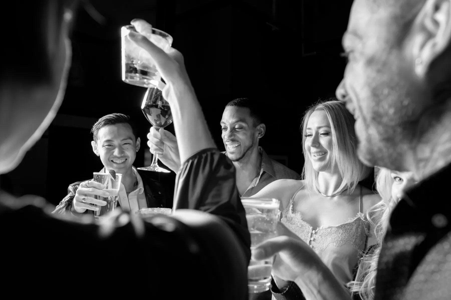 Colleagues raising cocktails together at a lively bar